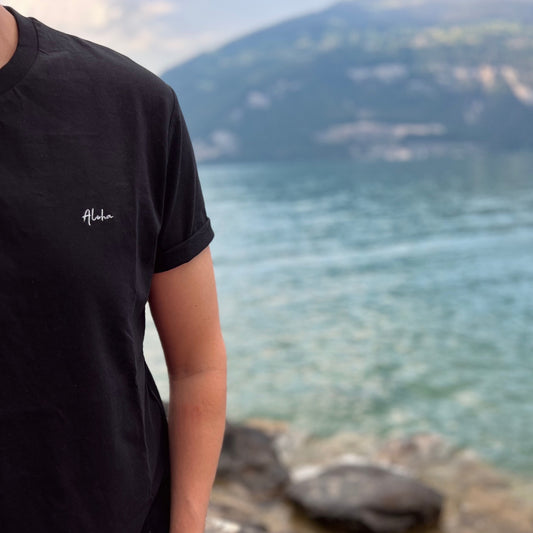 Mann im schwarzen 'The Aloha' T-Shirt, die perfekte Strandkleidung, am See