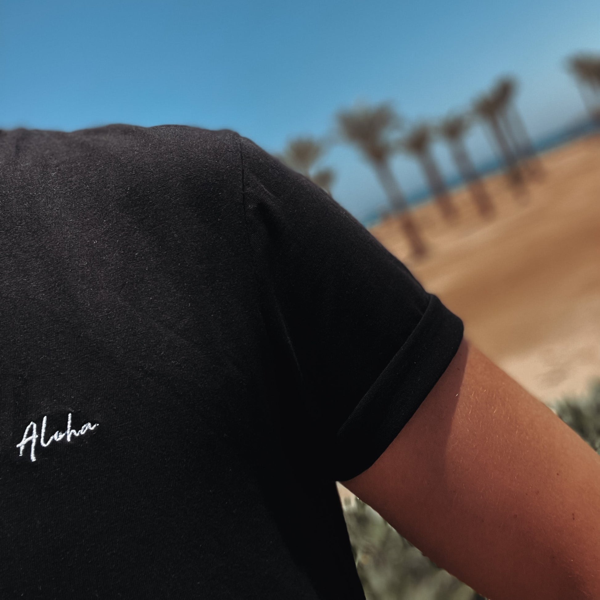 Elegante Strand-Accessoires: Mann im schwarzen T-Shirt zeigt den Aloha Spirit am Strand