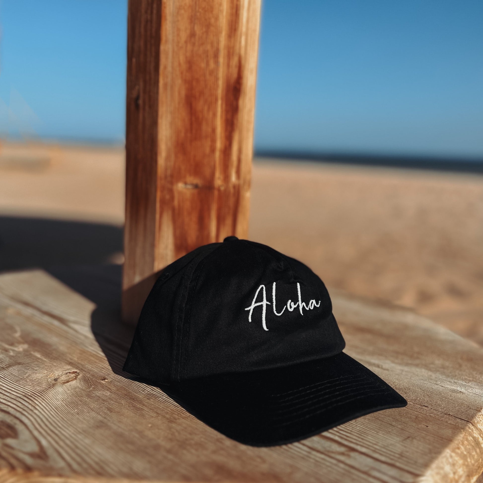 Aloha Cap in Strandumgebung auf einem Holzhocker – Tropisches Outfit Highlight